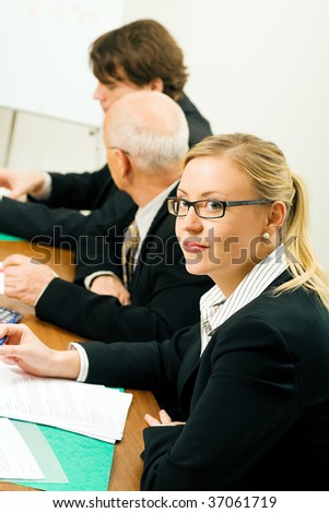 Businesspeople in a team meeting, a woman smiling at the camera
