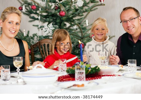 Family eating a traditional Christmas Dinner in front of the Christmas tree
