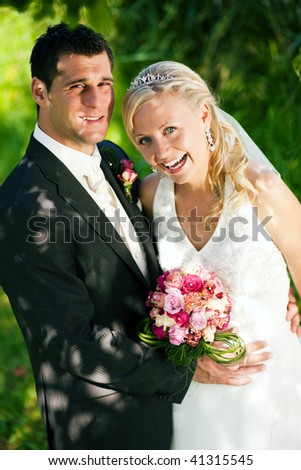 wedding couple looking at the viewer, the bride holding a bouquet of flowers in her hand