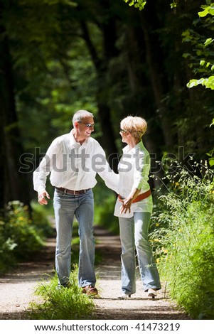 Mature or senior couple deeply in love having a walk holding each other tight in late spring or early summer