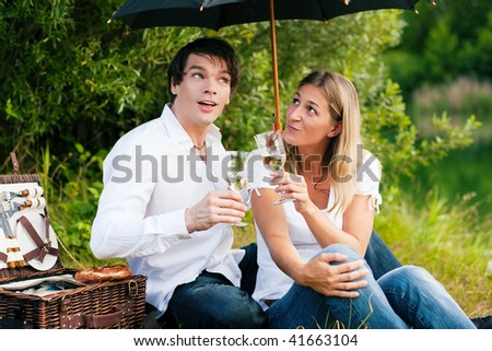 Couple sitting on a lake having a picnic - it is starting to rain but they do not care much