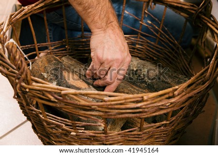 Man taking wood out of a basket to ignite the fireplace (only basket to be seen!)