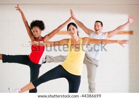 Group of three people in colorful cloths in a gym doing gymnastics