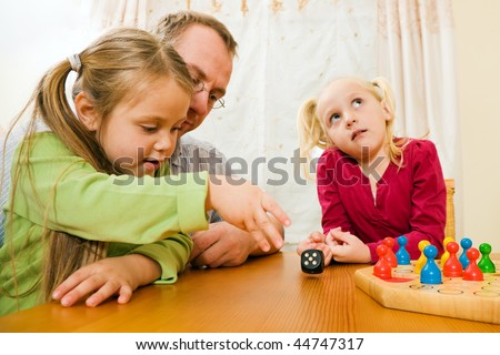 Family playing a board game at home in their leisure time, the setting is their living room