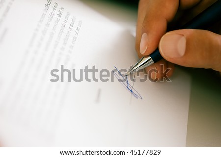 Man (only hand to be seen) signing a contract or another document (fake signature, focus on pen)