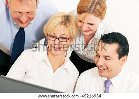 Team of four business people working in front a computer looking at the screen, seeing something good obviously