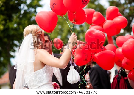 Happy wedding couple, they are holding balloons with good wishes written on them  in their hands and want to let them