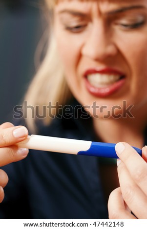 Woman looking at a pregnancy test being disappointed and angry upon the result, focus selective on test