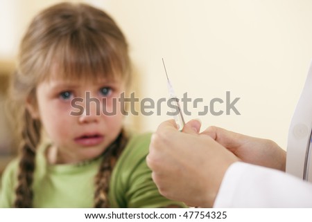 Doctor in his practice with syringe and a little girl child, she is very concerned and fearful of the treatment, and very understandably so (fokus on syringe!)