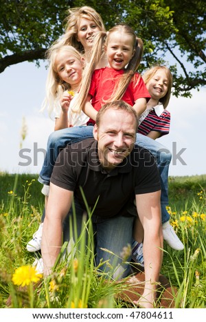Wife and daughters horse riding daddy - all of them looking happy, the father only a bit