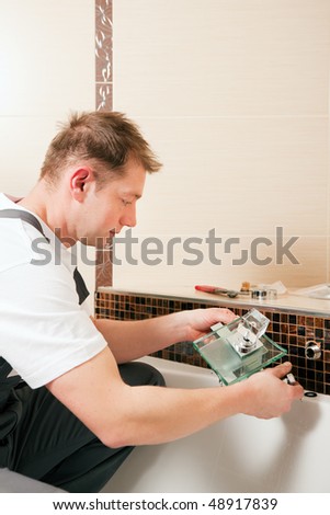 Plumber installing a mixer tap in a bathroom, he is sitting in the bathtub, focus on eyes of the man!