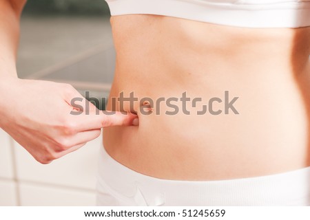 Woman is grabbing her love handles being not too satisfied with their status after a long winter - she will have to loose some weight