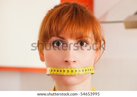 Woman gagged by a tape measure - symbol for eating disorder
