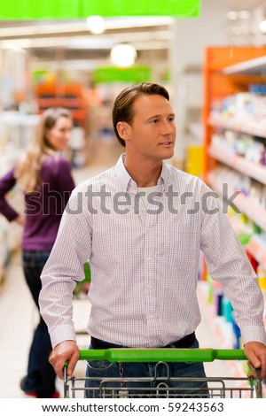Woman in the supermarket looking after a guy she just met shopping there, she is ready to flirt a bit