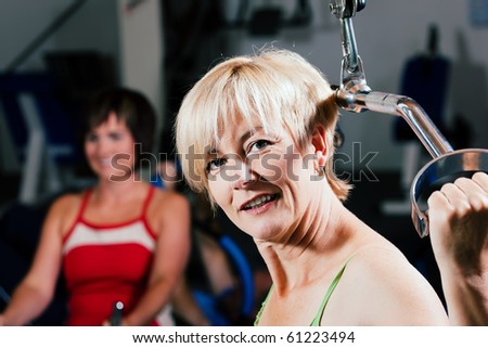 Senior woman in the gym lifting weights on a lat pull machine, exercising