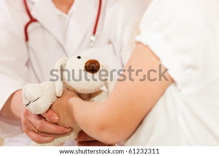 Doctor - Pediatrician - with a child patient in his practice, he is giving her a soft toy to calm down any fear