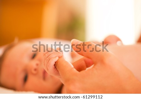 Baby grabbing the hand of her mother who is taking care of her (Focus is on hand)
