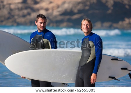Two surfers with their surf boards standing on the beach discussing the waves