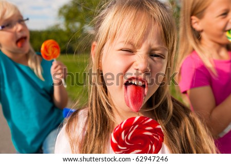  Three girls eating lollipops the girl in front sticking her tongue out