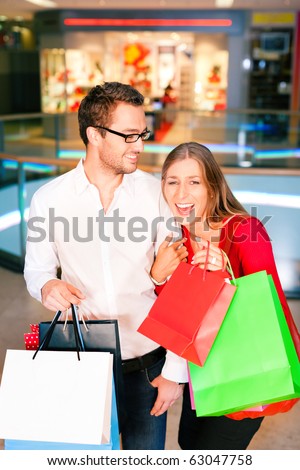 Couple - man and woman - in a shopping mall with colorful bags simply having fun
