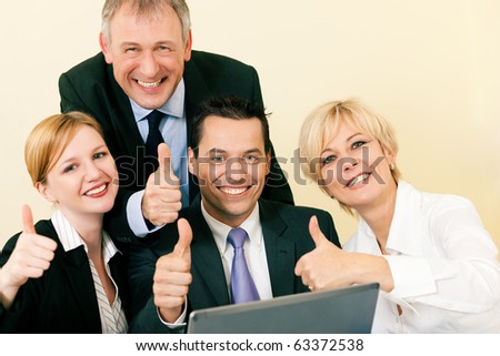 Business people in front of a laptop computer having a lot of fun and letting it show by doing the thumbs up sign, celebrating a success