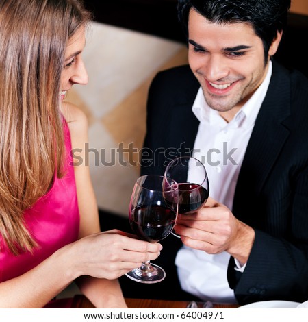 Young couple - man and woman - in a restaurant drinking glasses of red wine