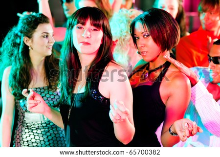 Dance action in a disco club - group of friends, men and women of different ethnicity, dancing to the music having lots of fun