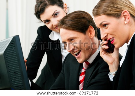 Small business team working in the office on their phones and computers in a shared project