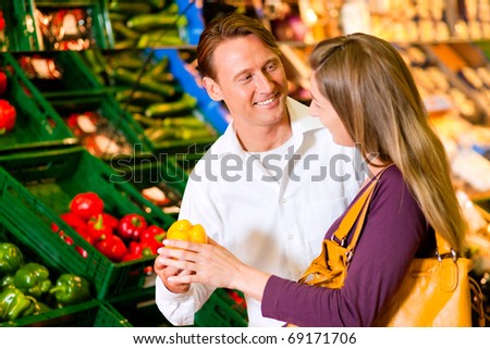 Couple in a supermarket at the vegetable shelf shopping for groceries, they are checking out the groceries