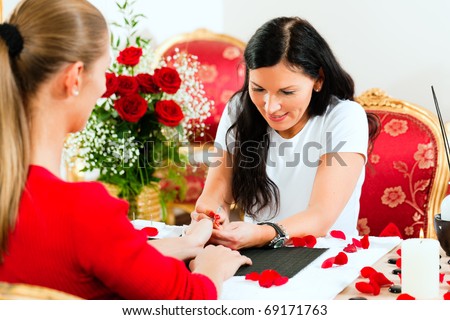 Woman in a nail salon receiving a manicure by a beautician, lots of roses in the background