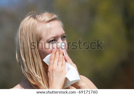 Woman with a flu or an allergy sneezing into her handkerchief in spring