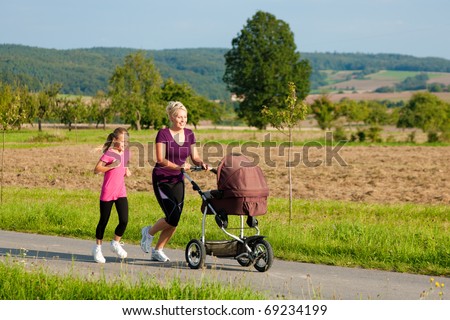 Family sport - mother and daughter jogging down a path with a baby stroller at a wonderful sunny day