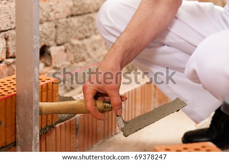 bricklayer laying bricks to make a wall, he is checking his work