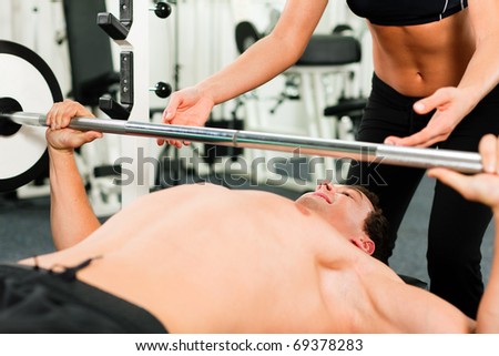man in gym with personal fitness trainer exercising power gymnastics with a barbell