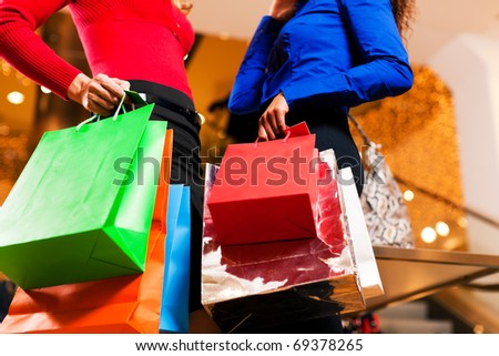 Two women in a shopping mall with colorful bags simply having fun