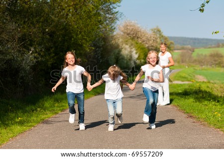 kids running down a path in spring, their mother standing in the background