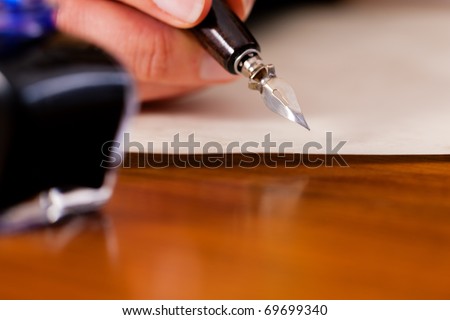 Woman (only hand to be seen) writing a letter on paper with a pen and ink, in the foreground she has an ink pot