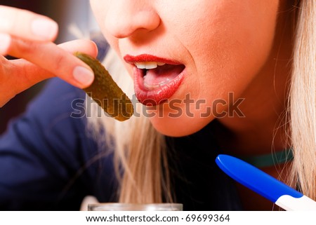 Pregnant woman - she hold a pregnancy test in her hand - is hungry for sour pickles due to change in her hormonal balance