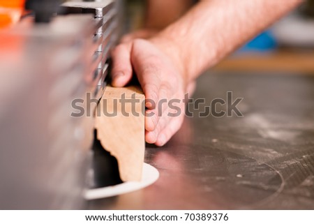 Carpenter - only hands to be seen - is standing on electric cutter; close up on the component part