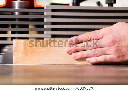 Carpenter - only hands to be seen - is standing on electric cutter; close up on the component part