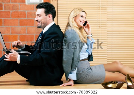 Couple Ã¢Â?Â? businesswoman and businessman Ã¢Â?Â? working at home sitting on the floor