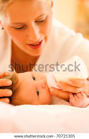 Mother is feeding her baby with a bottle; very tranquil scene