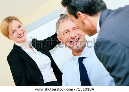 Business team receiving a presentation held by a female co-worker standing in front of a flipchart