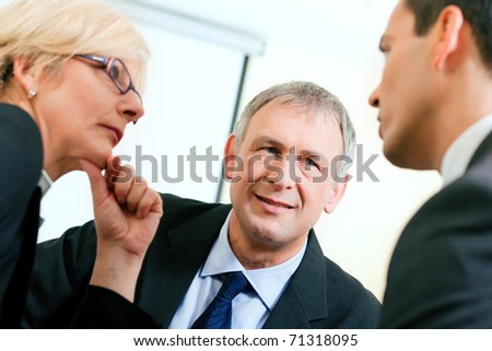 Small business team in the office in front of a whiteboard discussing a project