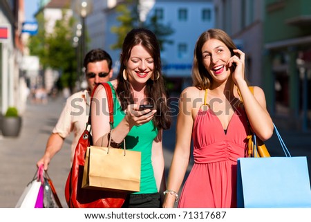 women downtown shopping with bags; a man is carrying the shopping bags