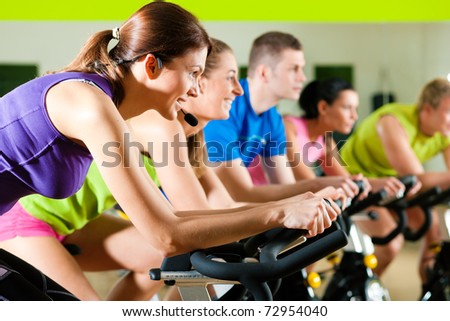 Group of five people in gym or fitness club exercising their legs doing cardio training Group of five people in gym or fitness club exercising their legs doing cardio training