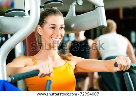 Woman doing fitness training on a butterfly machine with weights in gym or fitness club