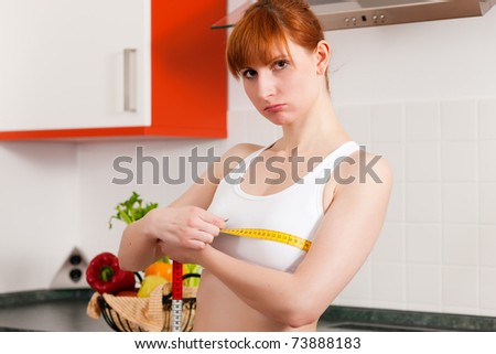 Thin woman measuring her chest with a tape measure, she seems to be unhappy