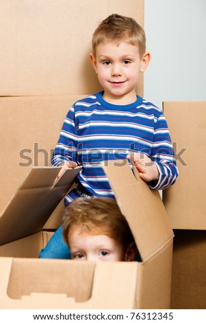 Family moving in their new home. The sons are playing with a moving box