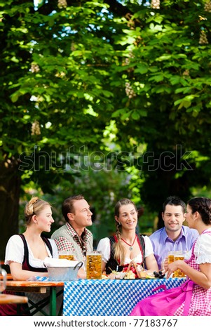 In Beer garden - friends Tracht, Dindl and on a table with beer and snacks in Bavaria, Germany